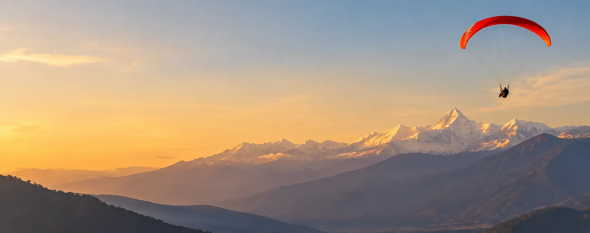 Paraglider flying over the Himalayas at sunset